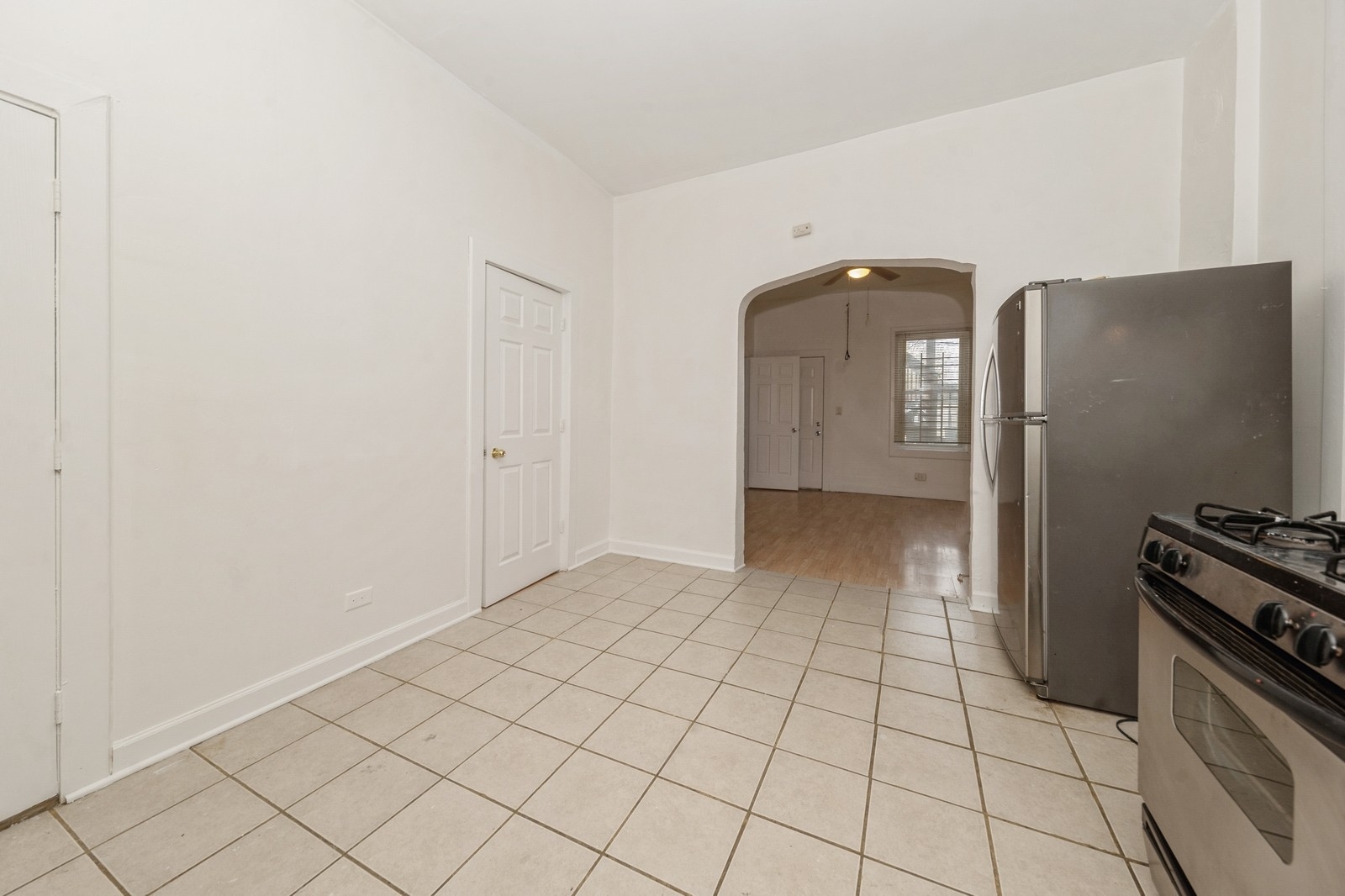 2242 West 19th Street, Unit 1R Chicago, IL 60608 - Photo 6 of 13 a view of a refrigerator in kitchen and an empty room in wooden floor