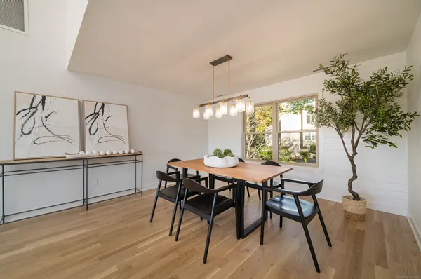 a view of a dining room and livingroom with furniture wooden floor a chandelier