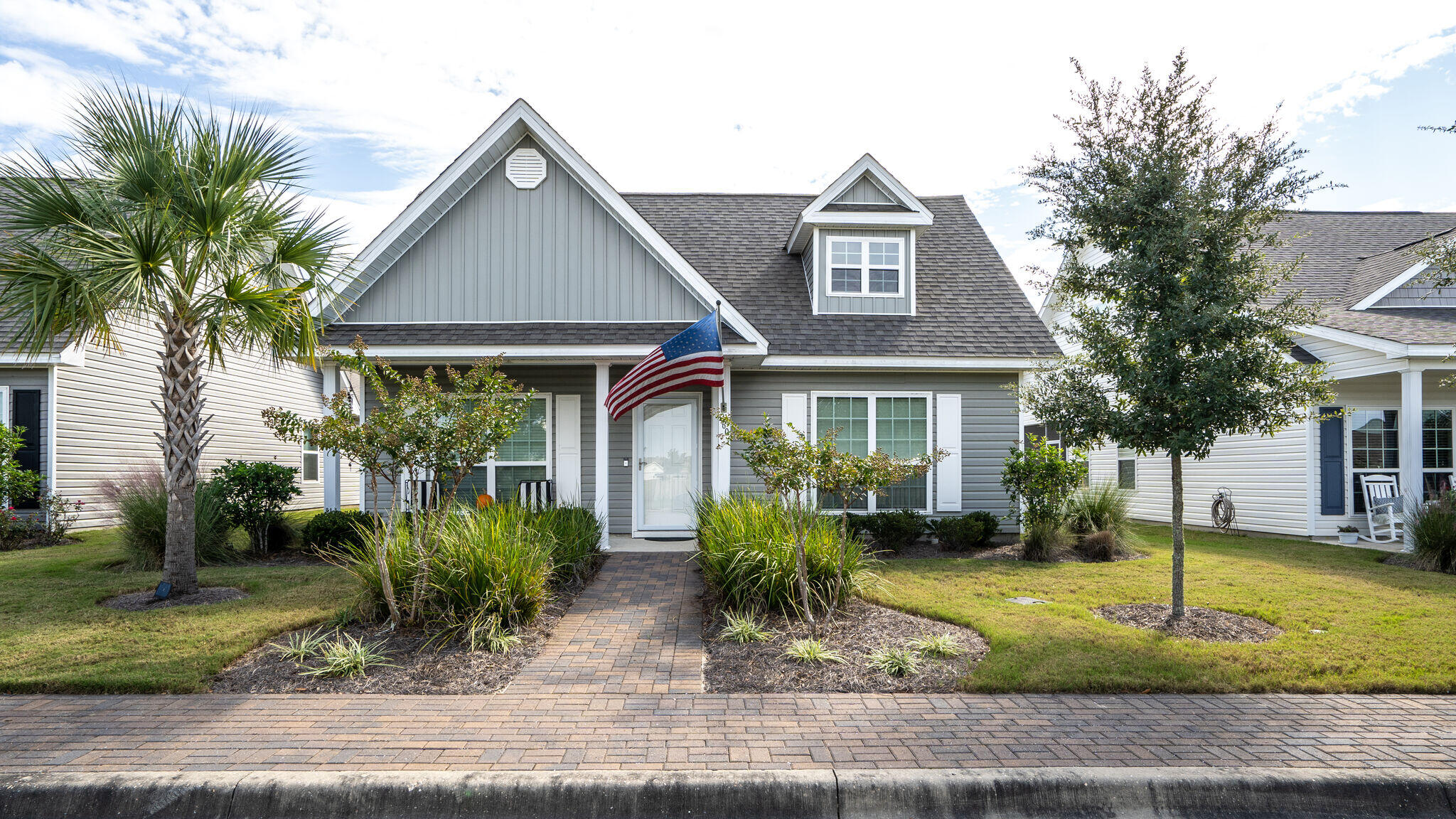 a front view of a house with a yard and potted plants
