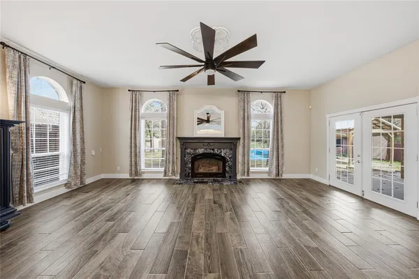 an empty room with wooden floor a fireplace and windows