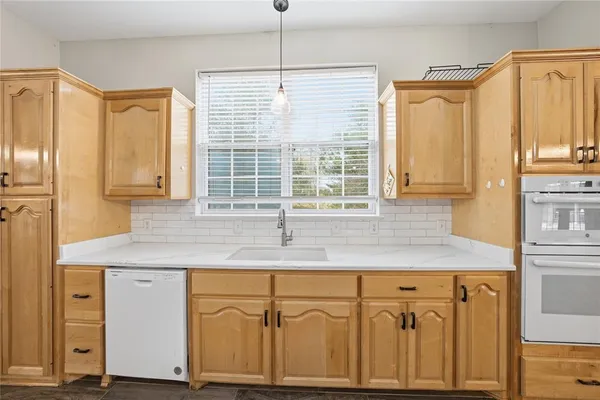 a kitchen with stainless steel appliances granite countertop a sink window and cabinets