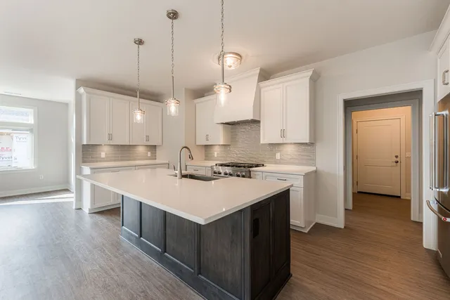 a kitchen with a stove a sink a center island and wooden floor
