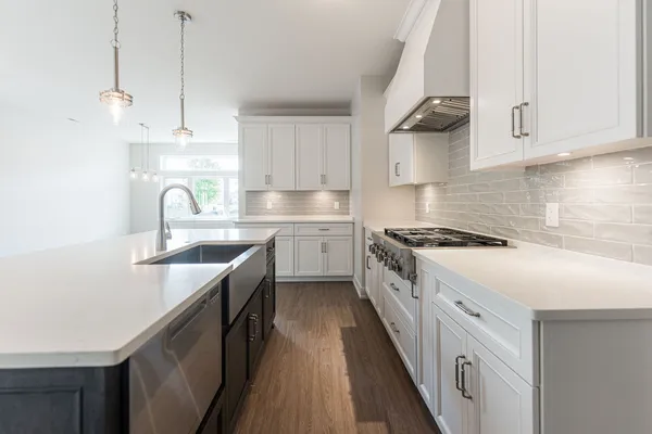a kitchen with kitchen island granite countertop a sink a counter space appliances and cabinets