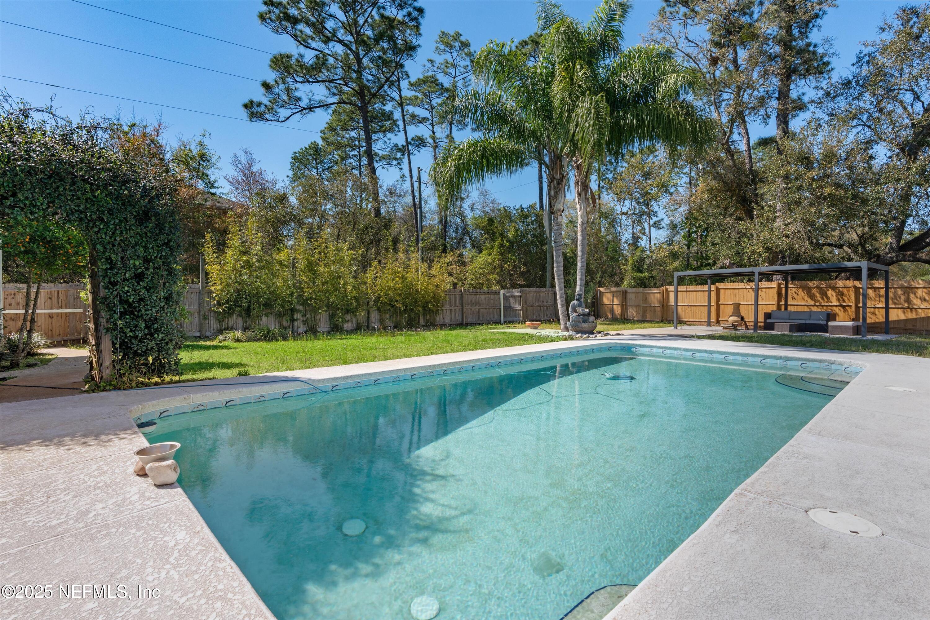 1216 Tumbleweed Drive Orange Park, FL 32065 - Photo 30 of 38 a view of a swimming pool with a yard and palm trees