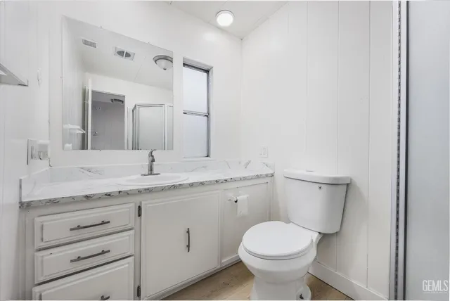 a bathroom with a granite countertop toilet sink and mirror