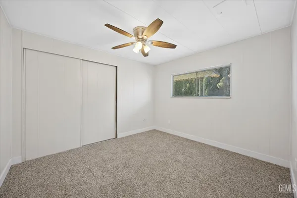 an empty room with windows and fan