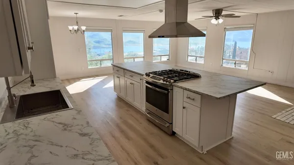 a kitchen with granite countertop a stove a sink a refrigerator and wooden floor