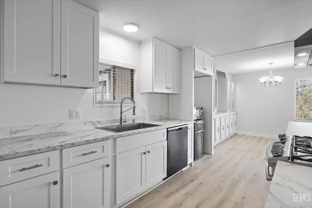 a kitchen with a sink dishwasher a stove and white cabinets with wooden floor