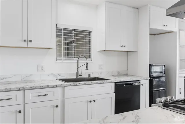 a kitchen with granite countertop white cabinets and a sink
