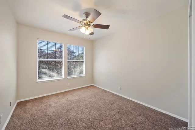 a view of an empty room with chandelier fan and fire place