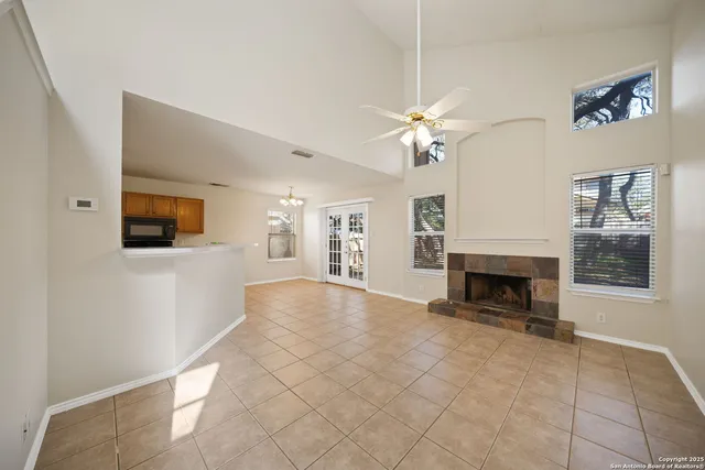a view of a livingroom with a fireplace a chandelier fan and windows
