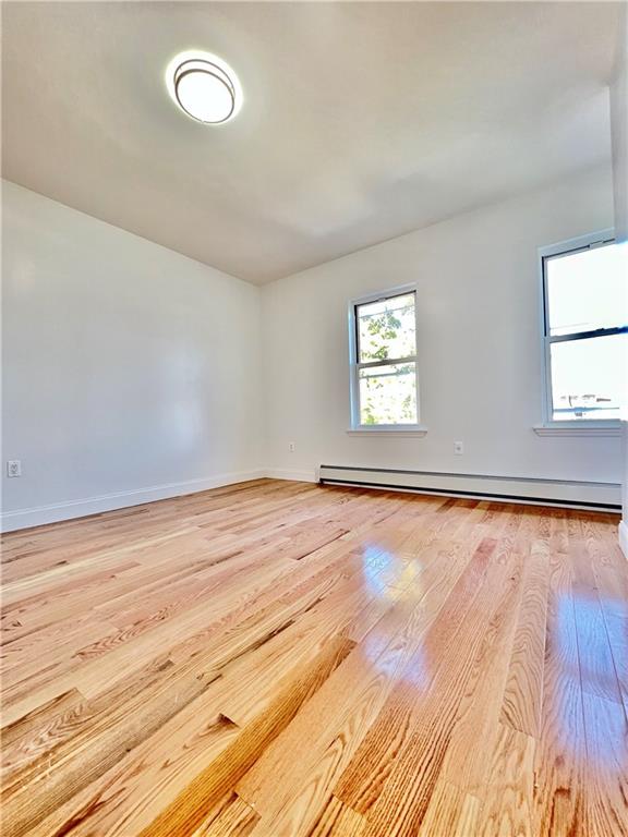 1651 85th Street Brooklyn, NY 11214 - Photo 11 of 17 an empty room with wooden floor and windows