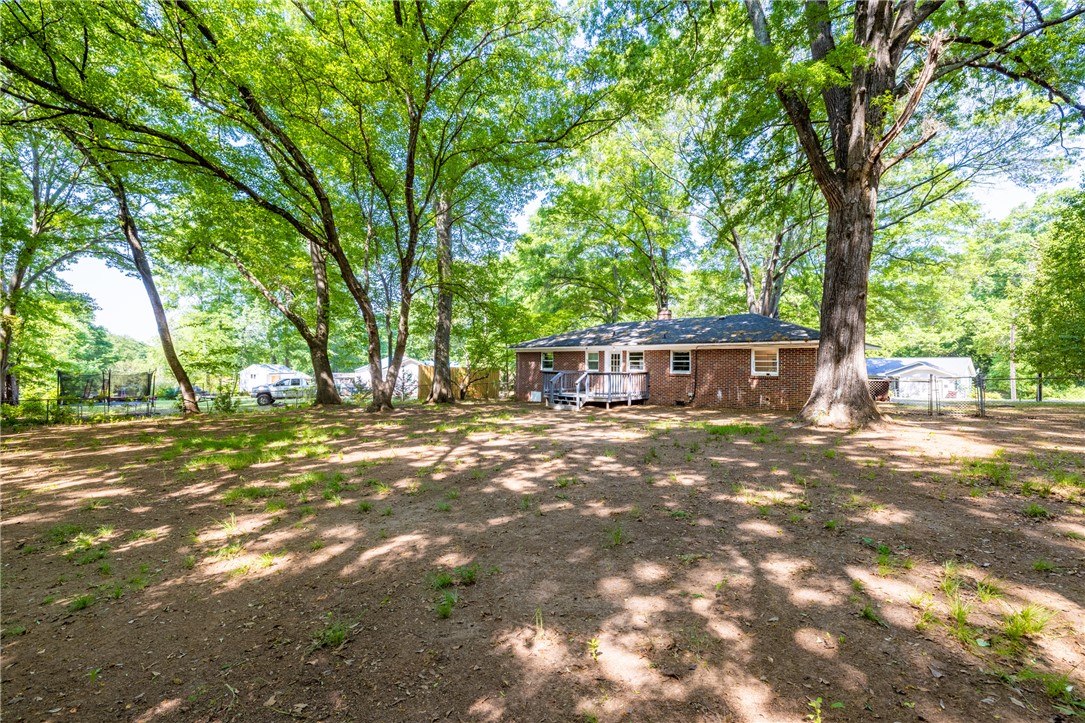 308 Buchanan Circle Pendleton, SC 29670 - Photo 17 of 19 Mature trees shade this expansive yard, providing a private outdoor retreat behind a classic brick home.