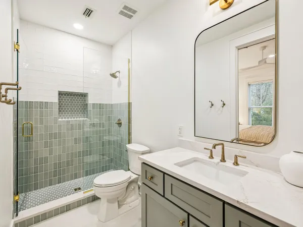a bathroom with a granite countertop sink a toilet and shower