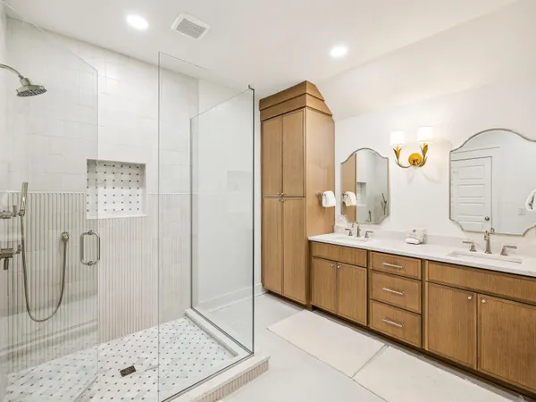 a bathroom with a double vanity sink mirror and shower
