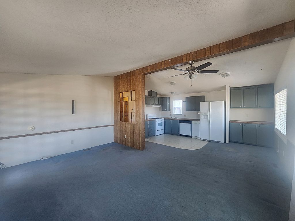 8257 Green Valley Road Mohave Valley, AZ 86440 - Photo 18 of 41 Open-concept living area featuring easy flow kitchen, casual dining area with built-in butler's pantry, blue carpeting and an exposed beam with wood-finish paneling