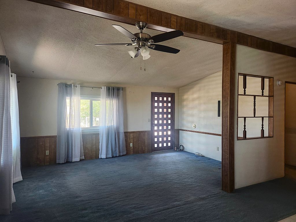 8257 Green Valley Road Mohave Valley, AZ 86440 - Photo 20 of 41 Open-concept living space featuring wood-panel wainscoting, a ceiling fan with integrated lighting, and a decorative room divider