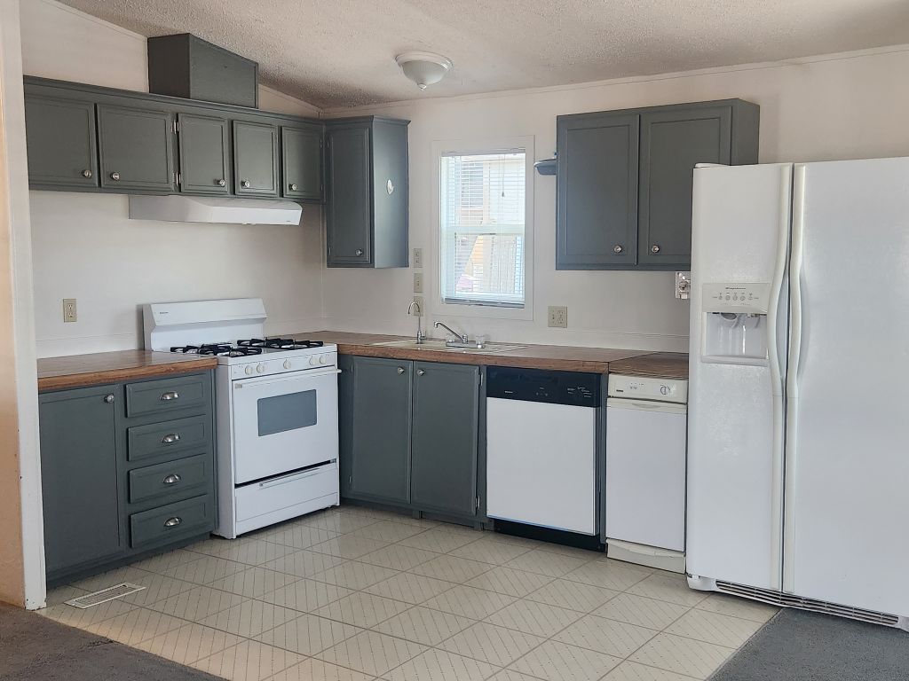 8257 Green Valley Road Mohave Valley, AZ 86440 - Photo 21 of 41 Kitchen featuring gray cabinetry, wood-finish laminate countertops, and white appliances including a gas range, dishwasher, trash compactor and refrigerator
