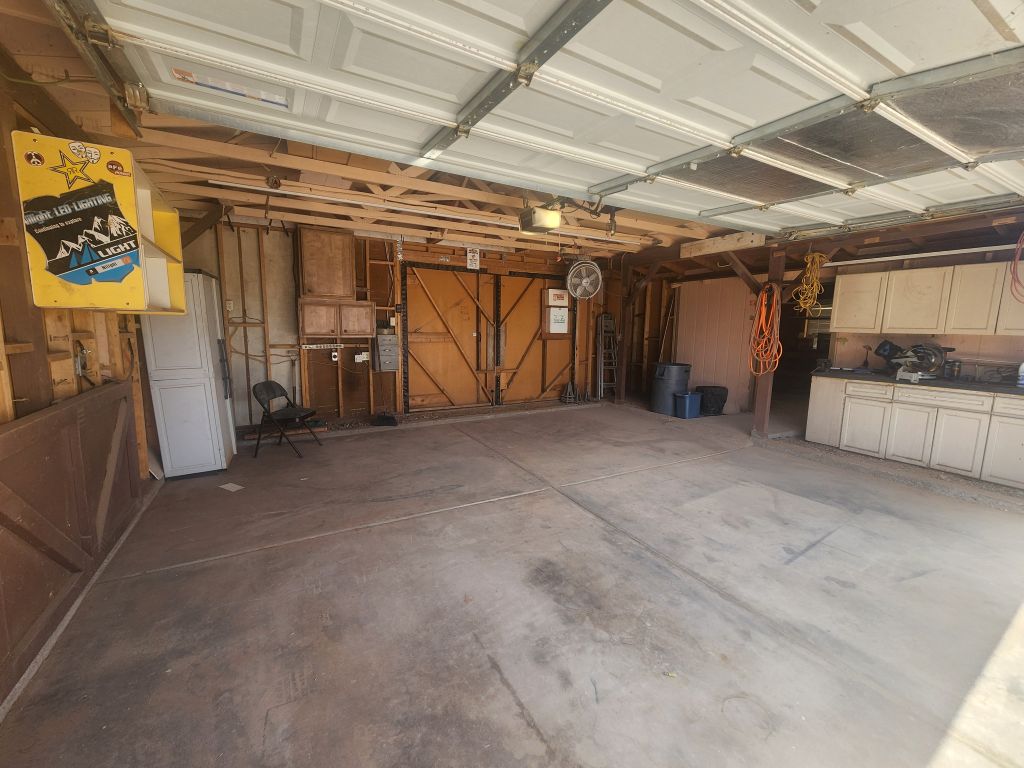 8257 Green Valley Road Mohave Valley, AZ 86440 - Photo 30 of 41 Garage featuring a pass-through door, exposed wood framing, work bench with built-in cabinetry, and a ceiling-mounted fan