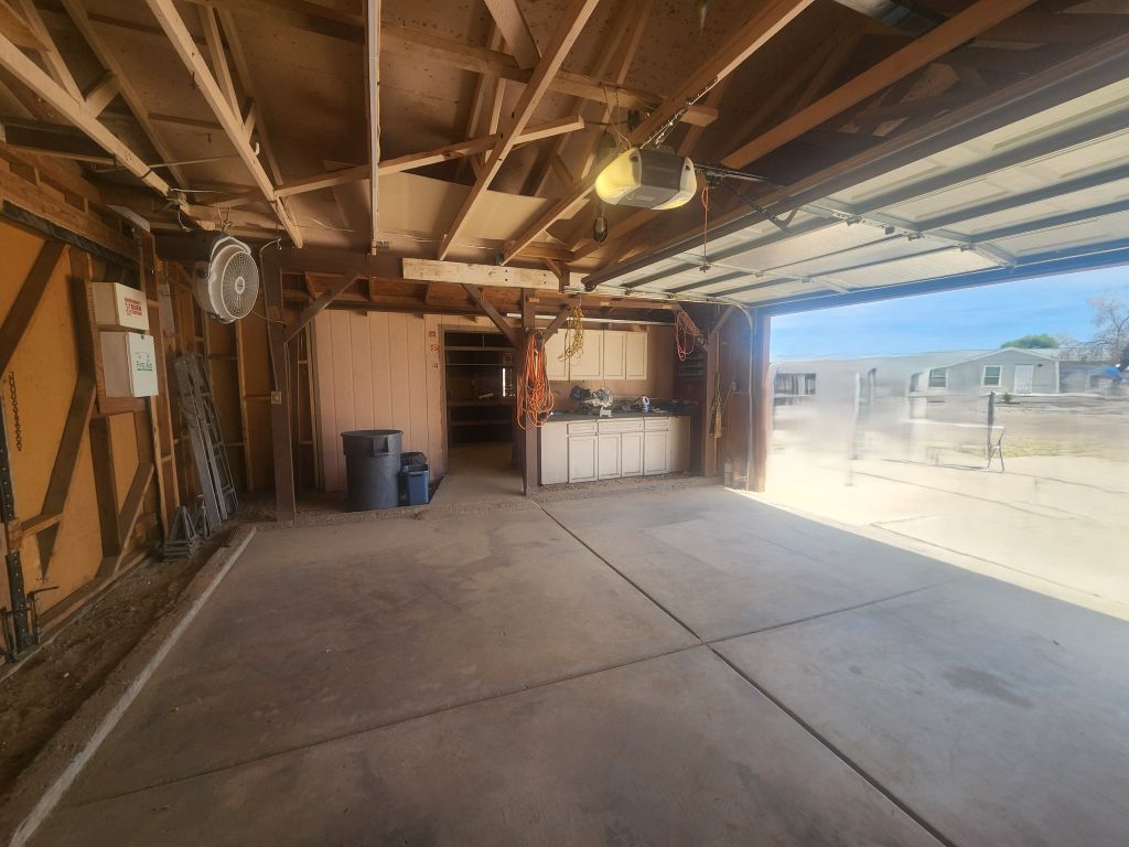 8257 Green Valley Road Mohave Valley, AZ 86440 - Photo 32 of 41 Garage featuring a work bench with built-in cabinets, entry to workshop area, concrete floor, exposed wood beam ceiling, and overhead lighting