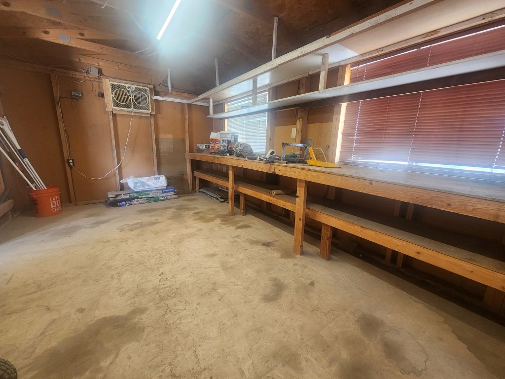 8257 Green Valley Road Mohave Valley, AZ 86440 - Photo 35 of 41 Spacious utility room featuring a concrete floor, built-in wooden workbench with shelving, exposed wood beam ceiling, and an integrated window air conditioning unit