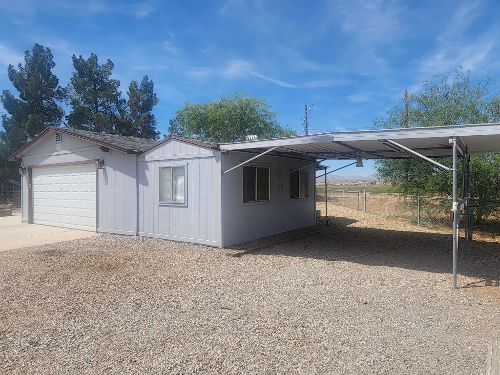 8257 Green Valley Road Mohave Valley, AZ 86440 - Photo 4 of 41 Exterior featuring a two-car garage with concrete driveway, attached covered carport, and gravel ground cover