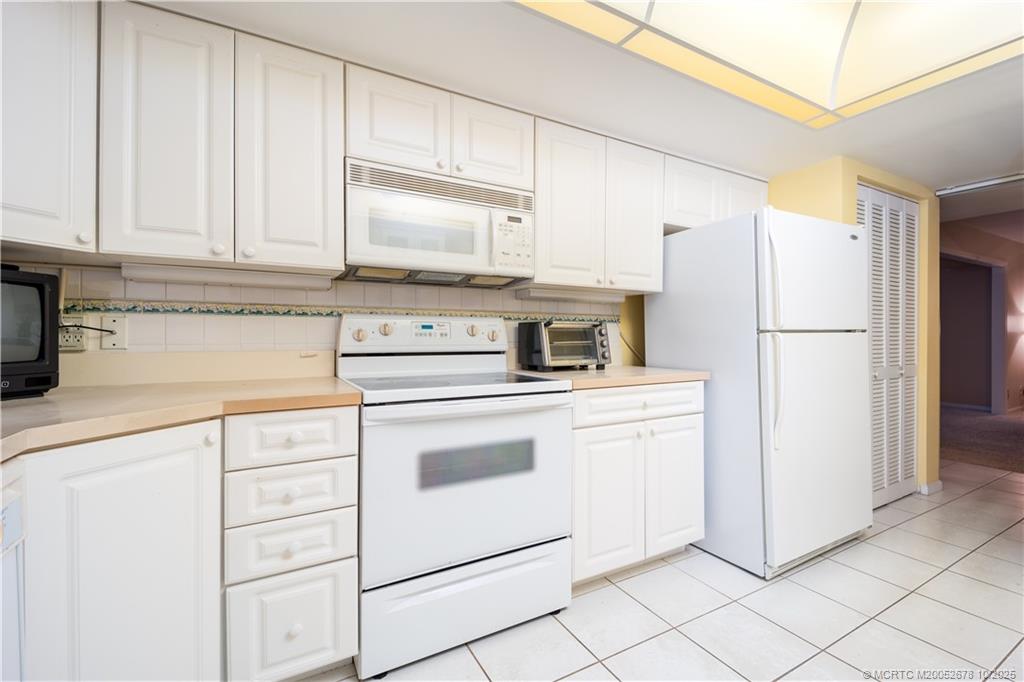 3100 Southeast Pruitt Road, Unit B301 Port St. Lucie, FL 34952 - Photo 31 of 48 a kitchen with white cabinets and white appliances