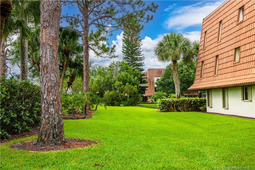3100 Southeast Pruitt Road, Unit B301 Port St. Lucie, FL 34952 - Photo 35 of 48 a view of a white house with a big yard plants and large trees