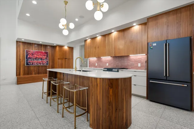 a kitchen with stainless steel appliances granite countertop a refrigerator a sink dishwasher a stove a dining table and chairs with wooden floor