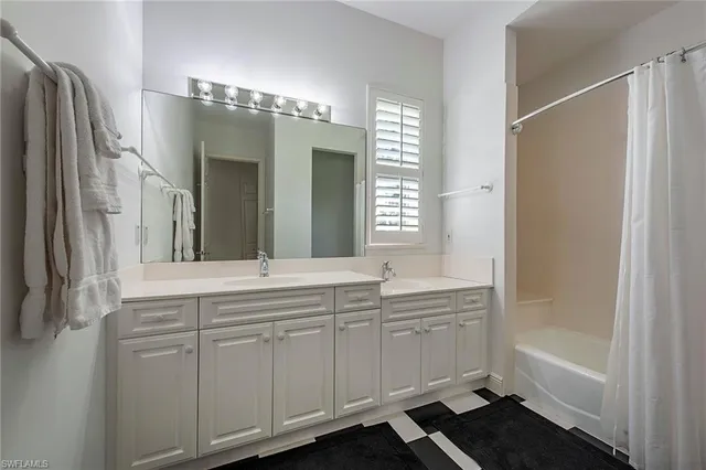 a bathroom with a double vanity sink mirror and bathtub