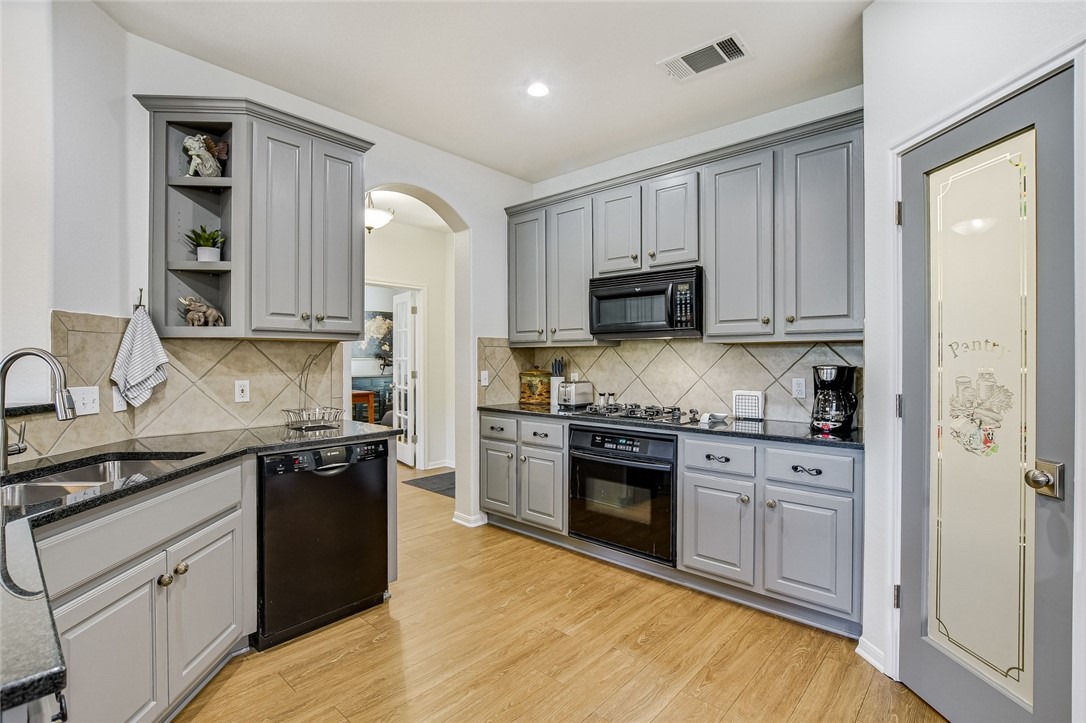 6405 York Bridge Circle Austin, TX 78749 - Photo 11 of 34 a kitchen with stainless steel appliances granite countertop a stove top oven a sink dishwasher and a refrigerator with wooden cabinets