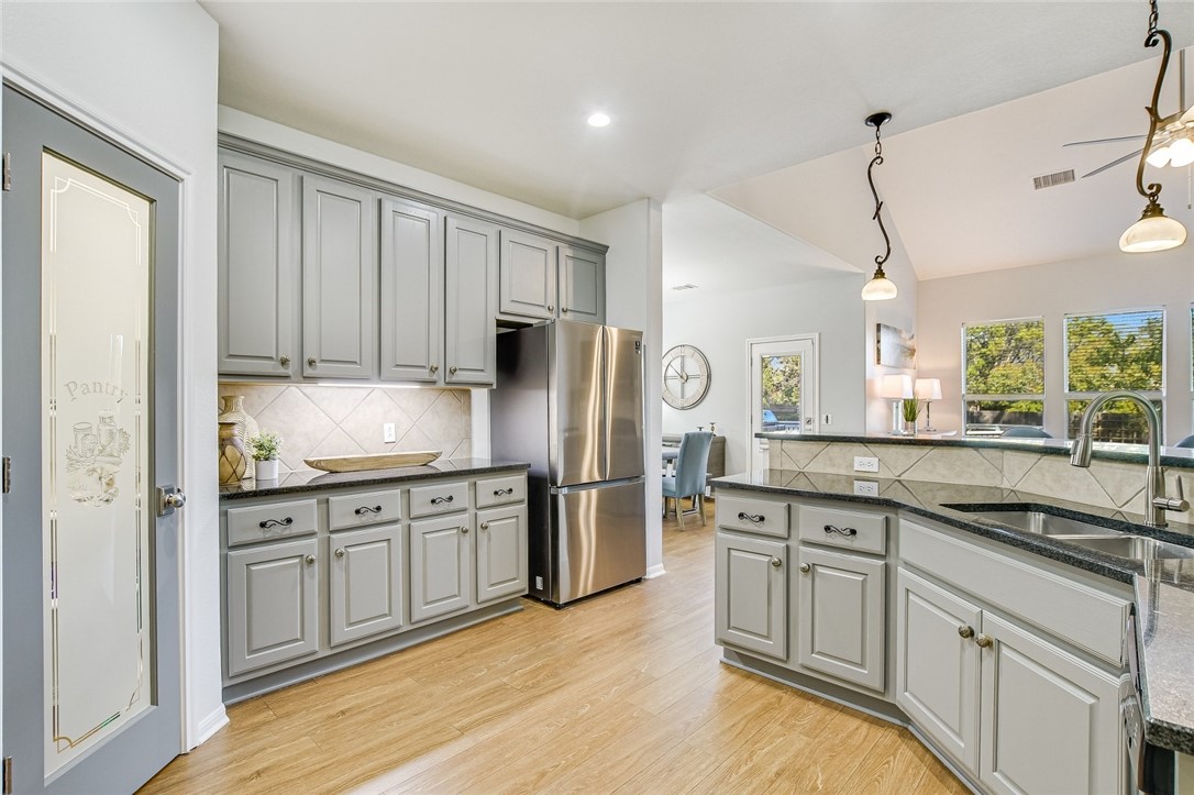 6405 York Bridge Circle Austin, TX 78749 - Photo 12 of 34 a kitchen with stainless steel appliances granite countertop a stove a sink and white cabinets with wooden floors