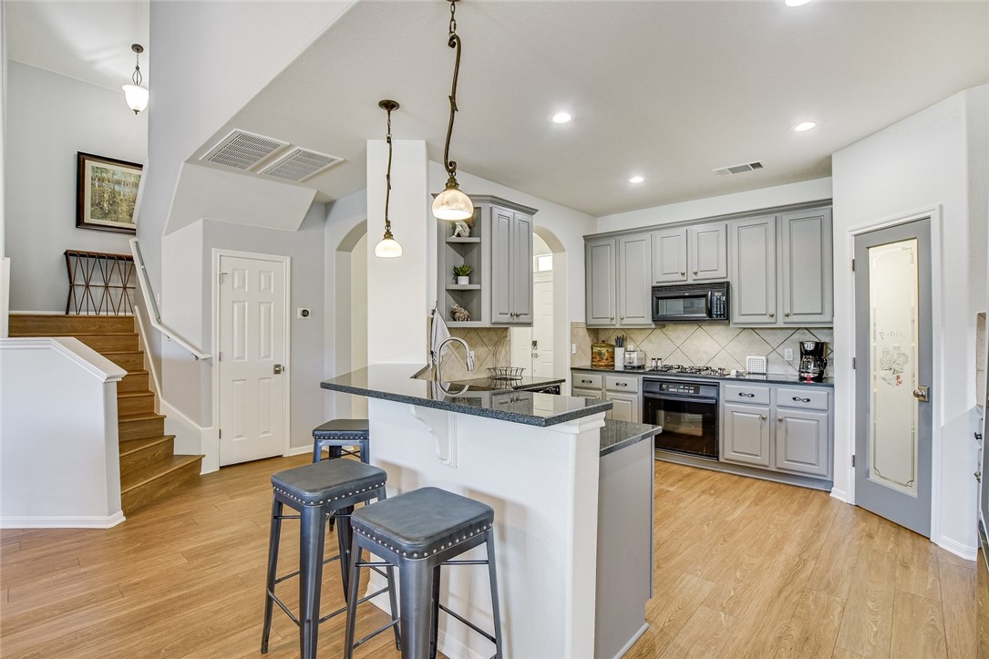 6405 York Bridge Circle Austin, TX 78749 - Photo 9 of 34 a kitchen with stainless steel appliances granite countertop a stove top oven a sink dishwasher a dining table and chairs with wooden floor