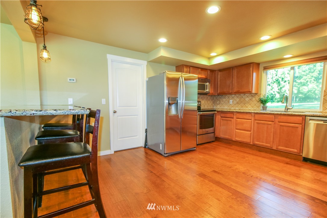27615 Webster Road East Graham, WA 98338 - Photo 11 of 36 a kitchen with stainless steel appliances granite countertop a refrigerator and a stove top oven