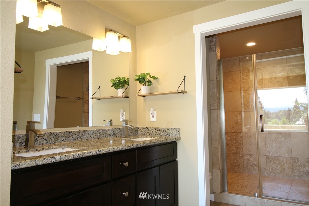 27615 Webster Road East Graham, WA 98338 - Photo 22 of 36 a bathroom with a granite countertop sink a mirror and a shower