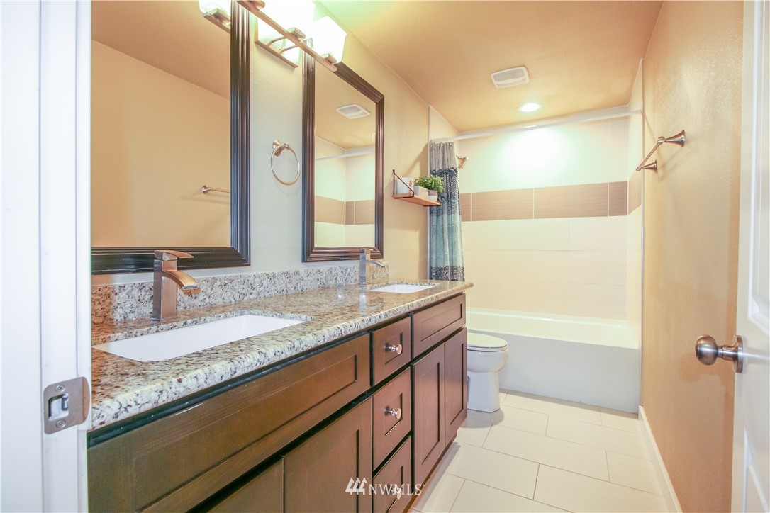 27615 Webster Road East Graham, WA 98338 - Photo 30 of 36 a bathroom with a granite countertop sink a mirror and a bathtub