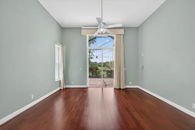 a view of an empty room with window wooden floor and a chandelier fan