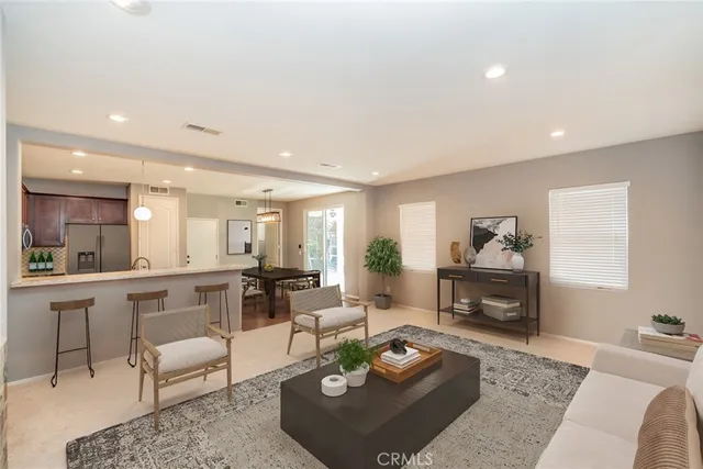 a living room with furniture a rug kitchen view and a table