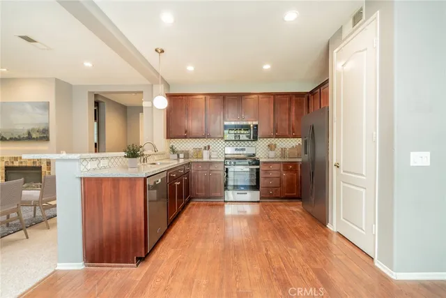 a kitchen with stainless steel appliances granite countertop wooden cabinets a sink a stove a refrigerator and a microwave