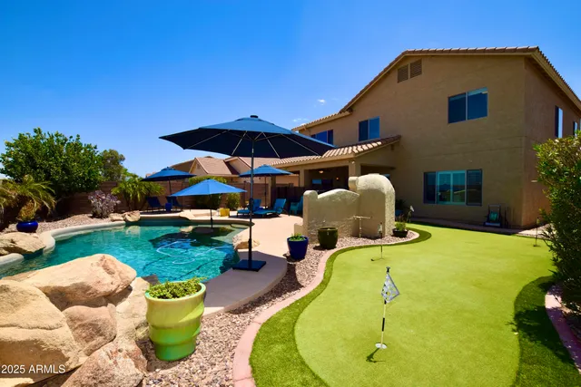 a view of swimming pool in the backyard with lawn chairs