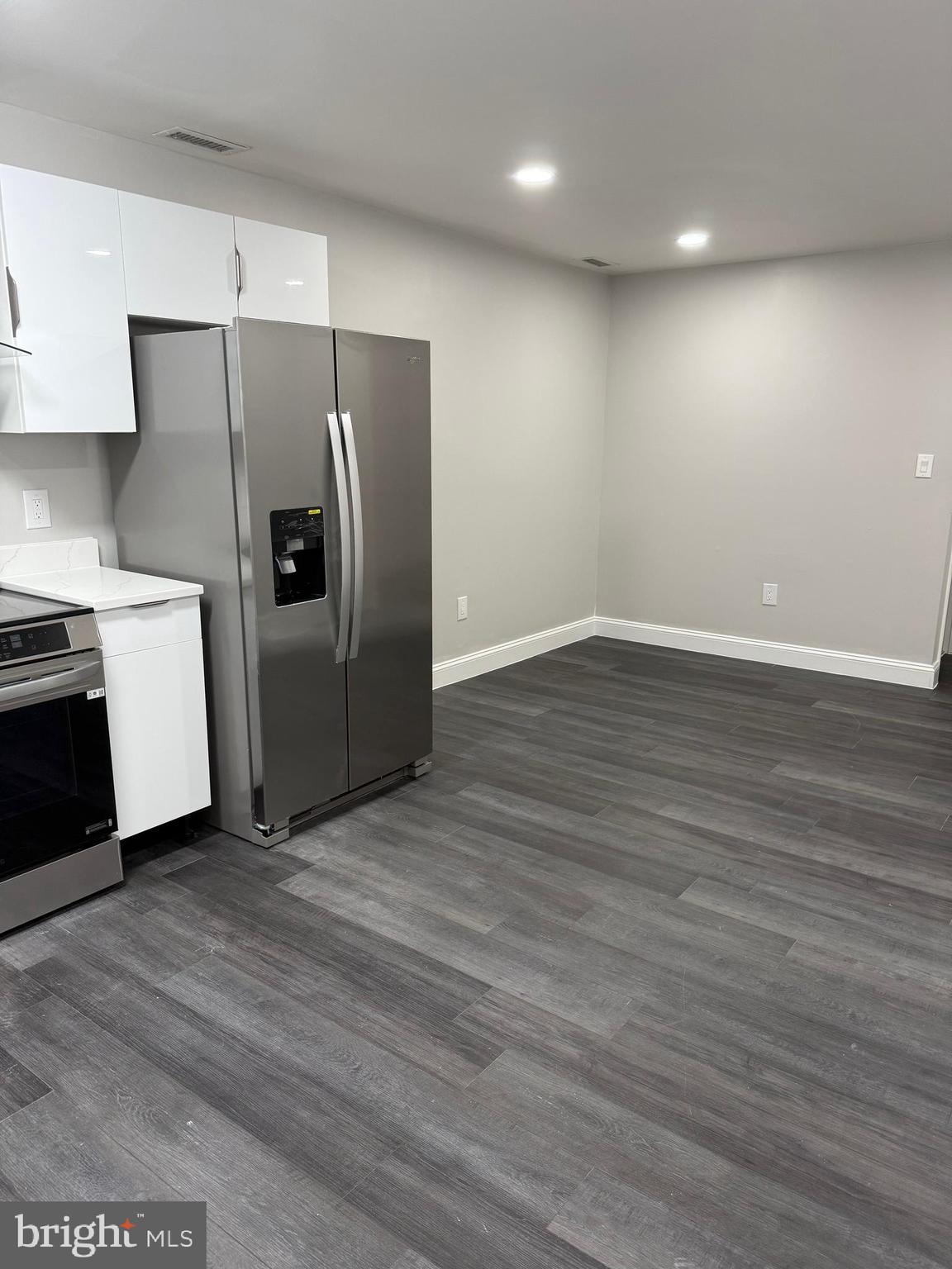 2511 Maryland Avenue, Unit 3 Baltimore, MD 21218 - Photo 3 of 11 a view of a refrigerator in kitchen and an empty room with wooden floor