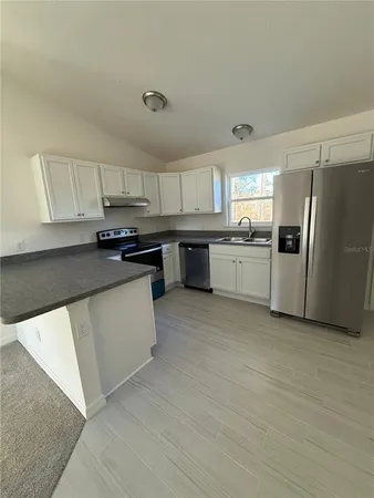 a kitchen with a refrigerator a sink a stove a microwave a counter top space and cabinets