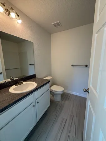a bathroom with a granite countertop toilet a sink and a mirror