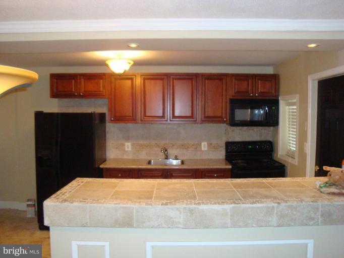 5749 Maplehill Road Baltimore, MD 21239 - Photo 2 of 15 a kitchen with granite countertop a refrigerator and a stove top oven