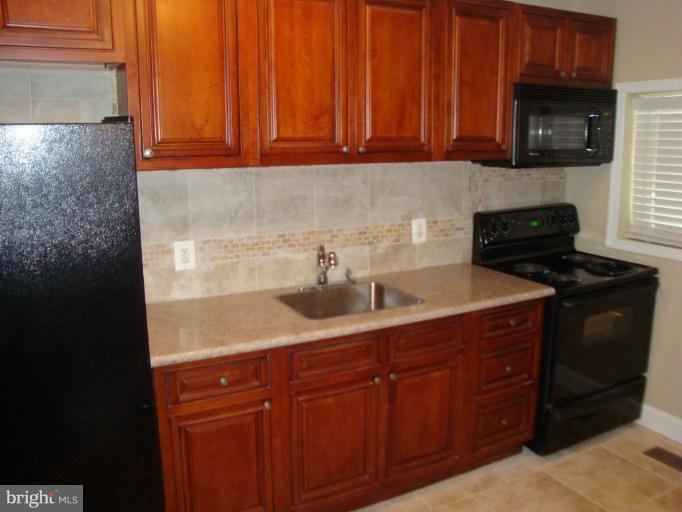 5749 Maplehill Road Baltimore, MD 21239 - Photo 5 of 15 a kitchen with stainless steel appliances granite countertop wooden cabinets a stove a sink and dishwasher