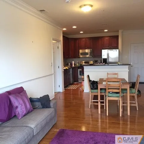 a living room with stainless steel appliances furniture and a view of kitchen