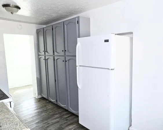 a view of a kitchen with refrigerator and wooden floor