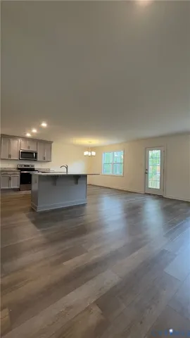 a view of kitchen and empty room with wooden floor