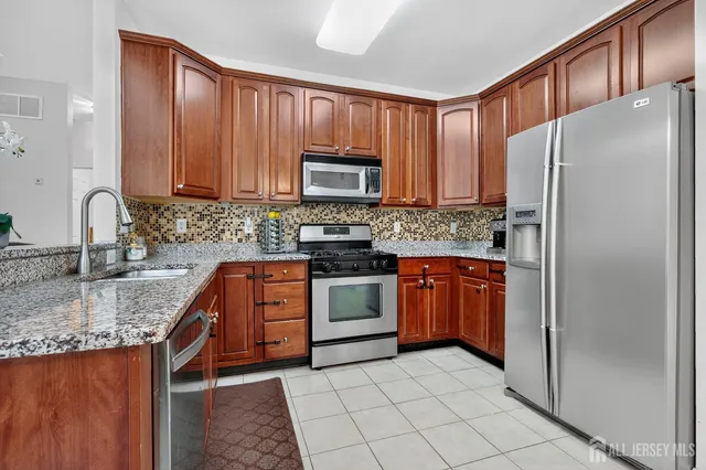a kitchen with granite countertop a refrigerator stove top oven and sink
