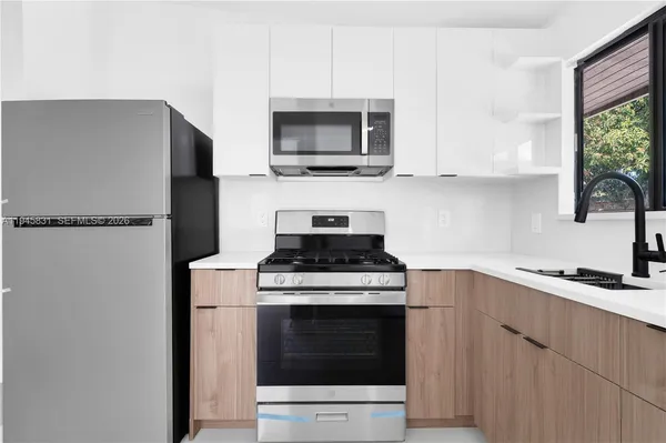 a kitchen with stainless steel appliances a stove a microwave and a sink